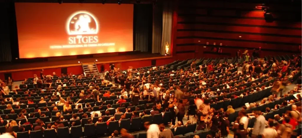 Auditorio del Festival Internacional de Cine de Sitges lleno de público con la pantalla iluminada con el logotipo del festival.