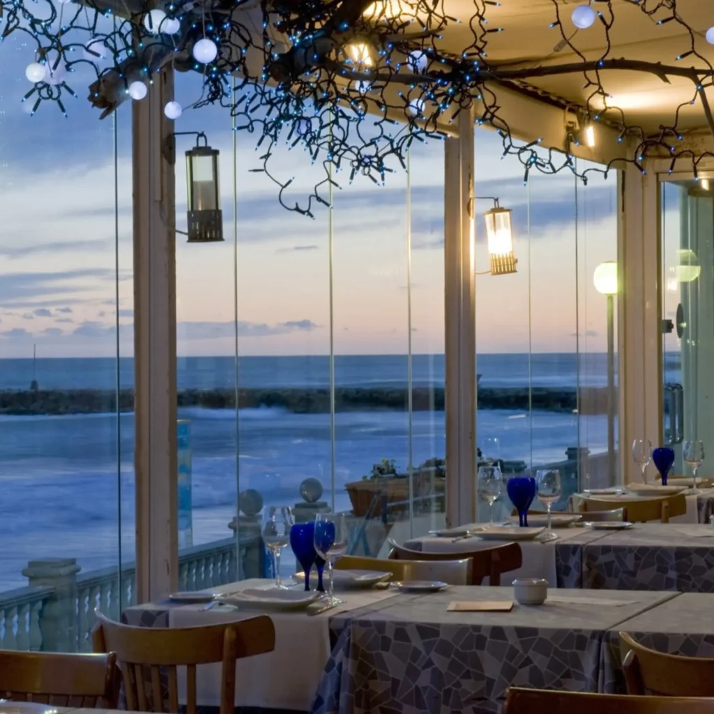 Terraza de un restaurante al aire libre decorada con guirnaldas de luces y faroles en ambiente nocturno.