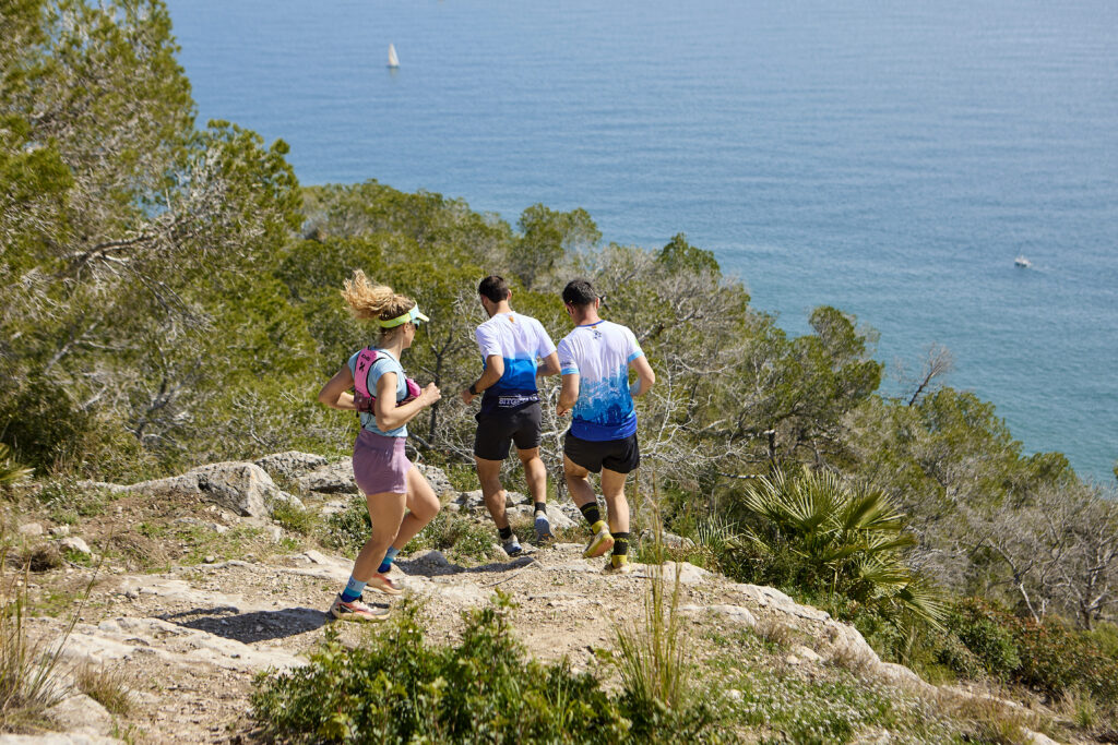 res corredors practicant trail running pel Parc del Garraf amb el mar Mediterrani al fons