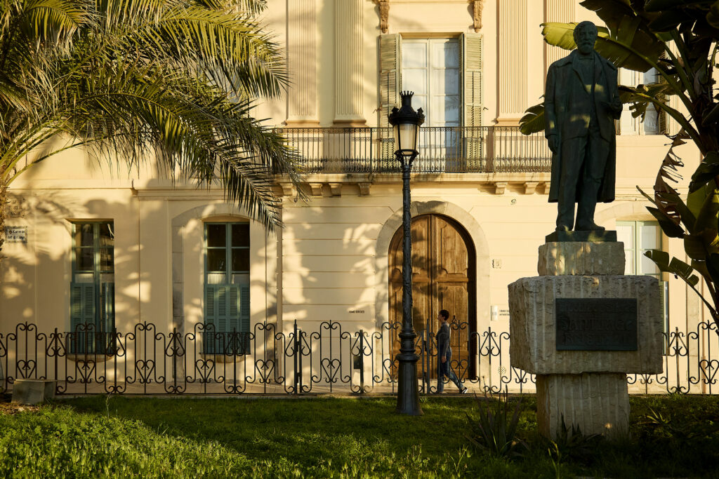 Monument a Santiago Rusiñol davant d’un edifici històric de Sitges