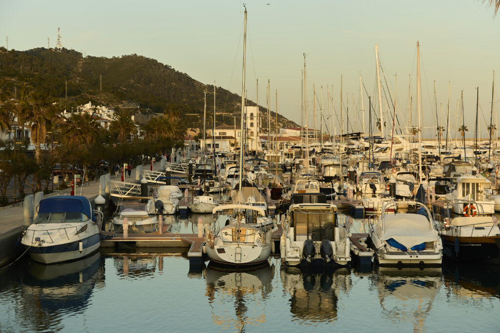 Vista del Port de Sitges-Aiguadolç amb embarcacions amarrades i el massís del Garraf al fons