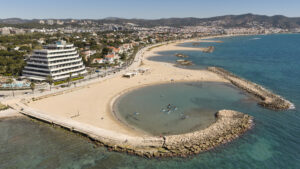 Vista aèria de les platges i el passeig marítim de Sitges amb el massís del Garraf al fons