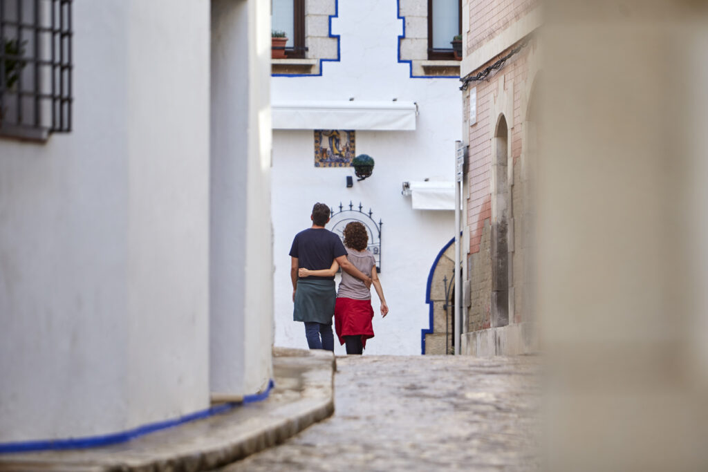 Parella passejant abraçada pels carrers del nucli antic de Sitges.