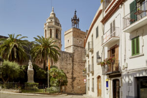 Campanar i façanes del nucli antic de Sitges, amb palmeres i arquitectura tradicional